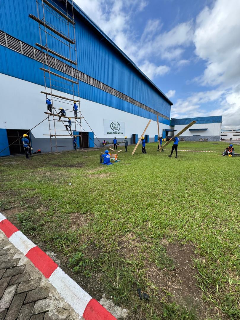Équipe et échafaudage devant un bâtiment industriel